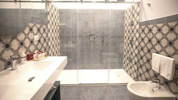 A bathroom with a large shower, a sink, and a bidet.