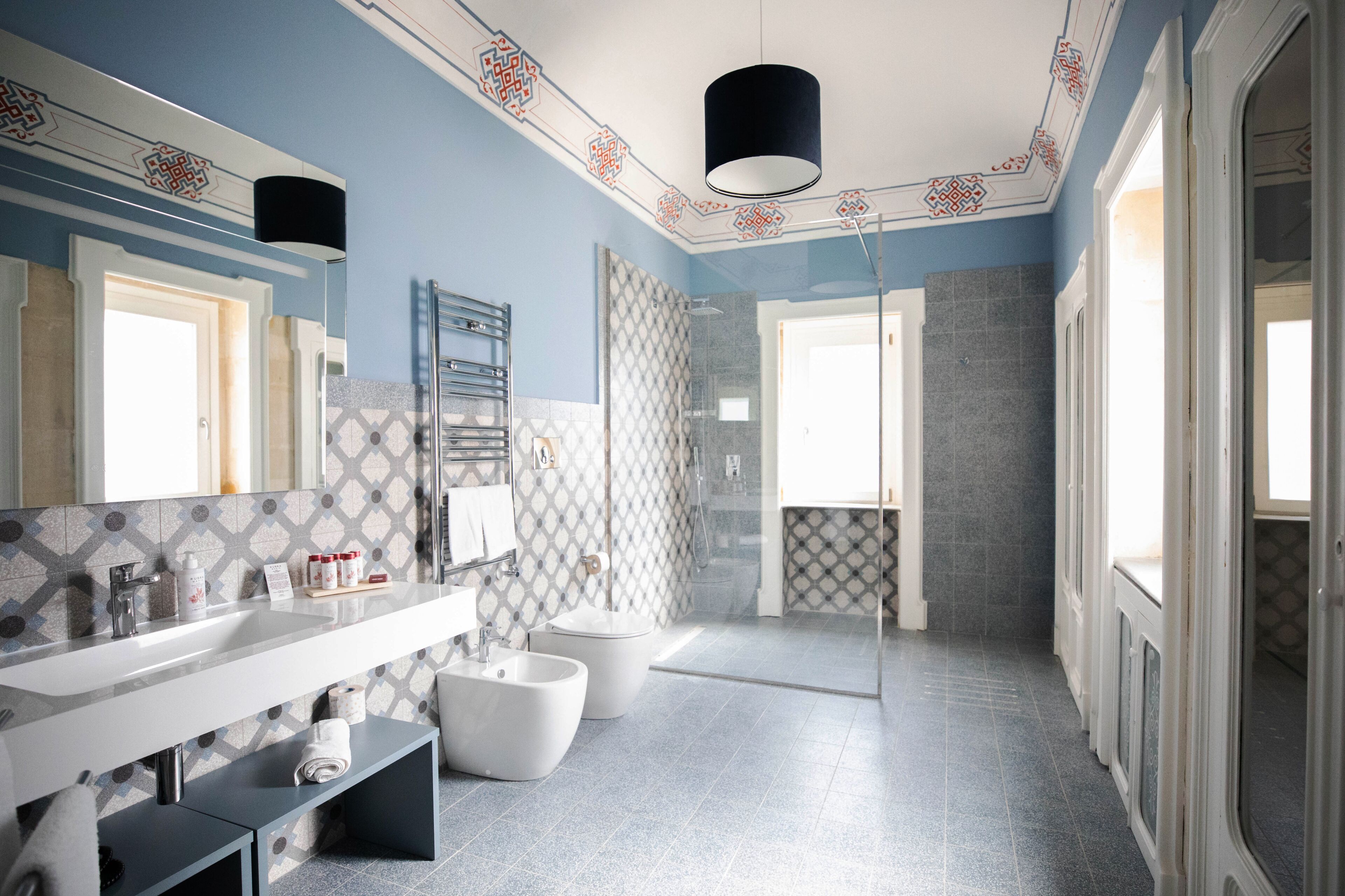 Een moderne badkamer met een grote spiegel, een witte wastafel, een toiletbril en een douchehoek.