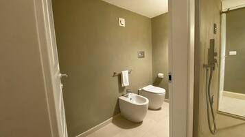 A bathroom with a bidet, toilet, and shower.