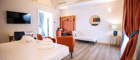 A hotel room with two beds, a TV, a wardrobe, a sofa, and a mirror.
