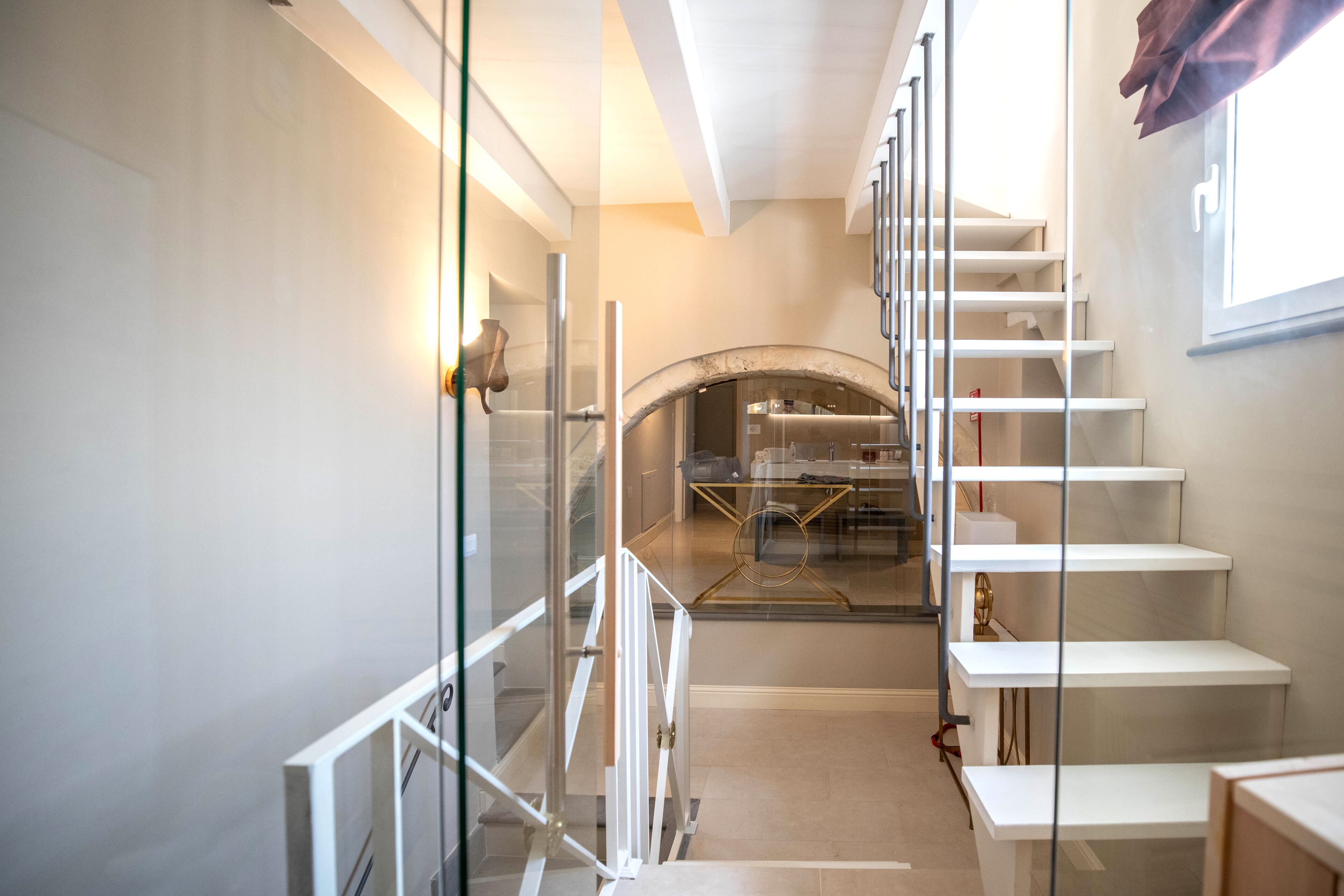 Un intérieur moderne avec une cloison en verre, un escalier et un coin repas doté d’une table ronde.