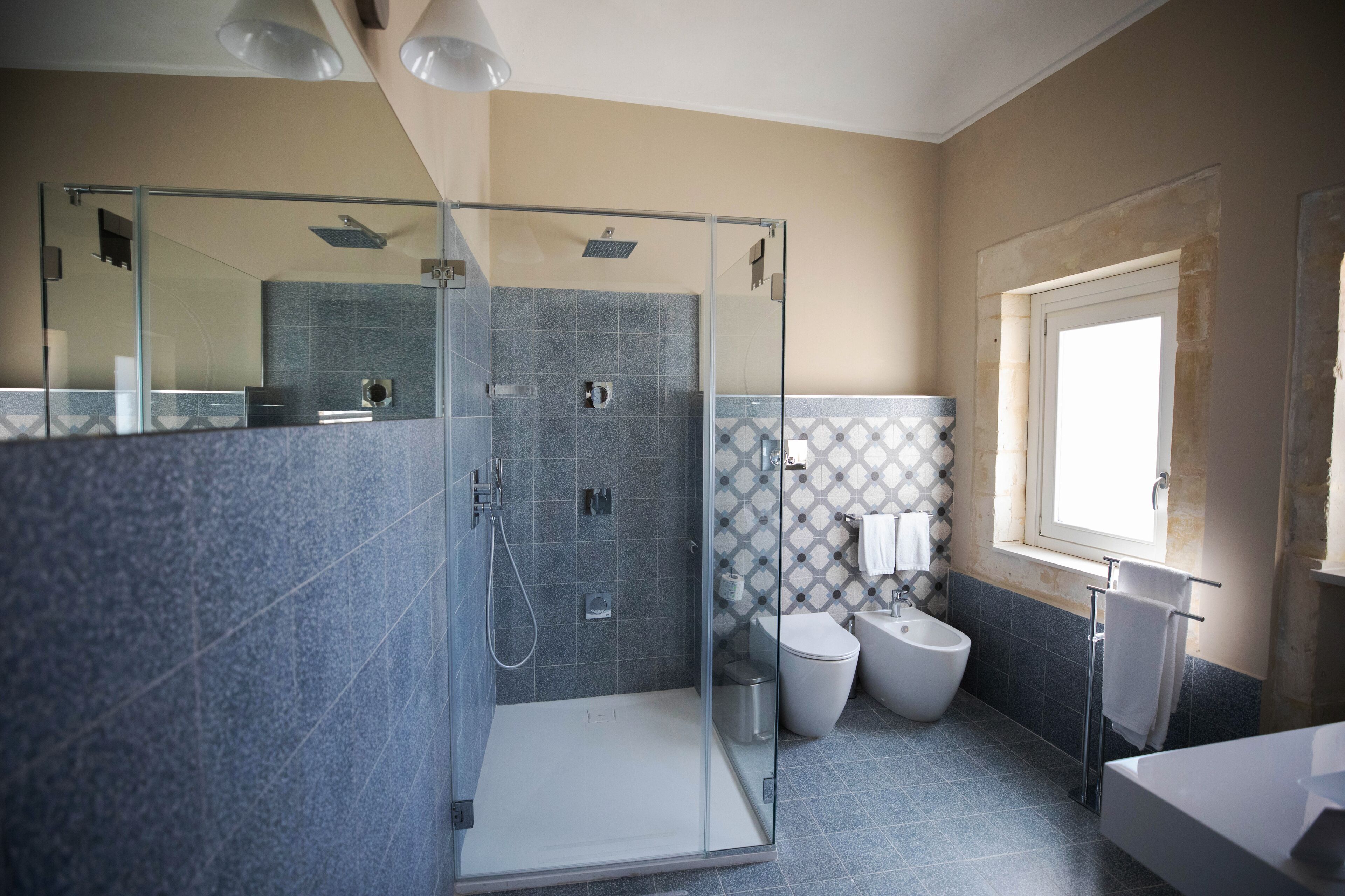 A modern bathroom with a glass-enclosed shower, a toilet, and a sink.