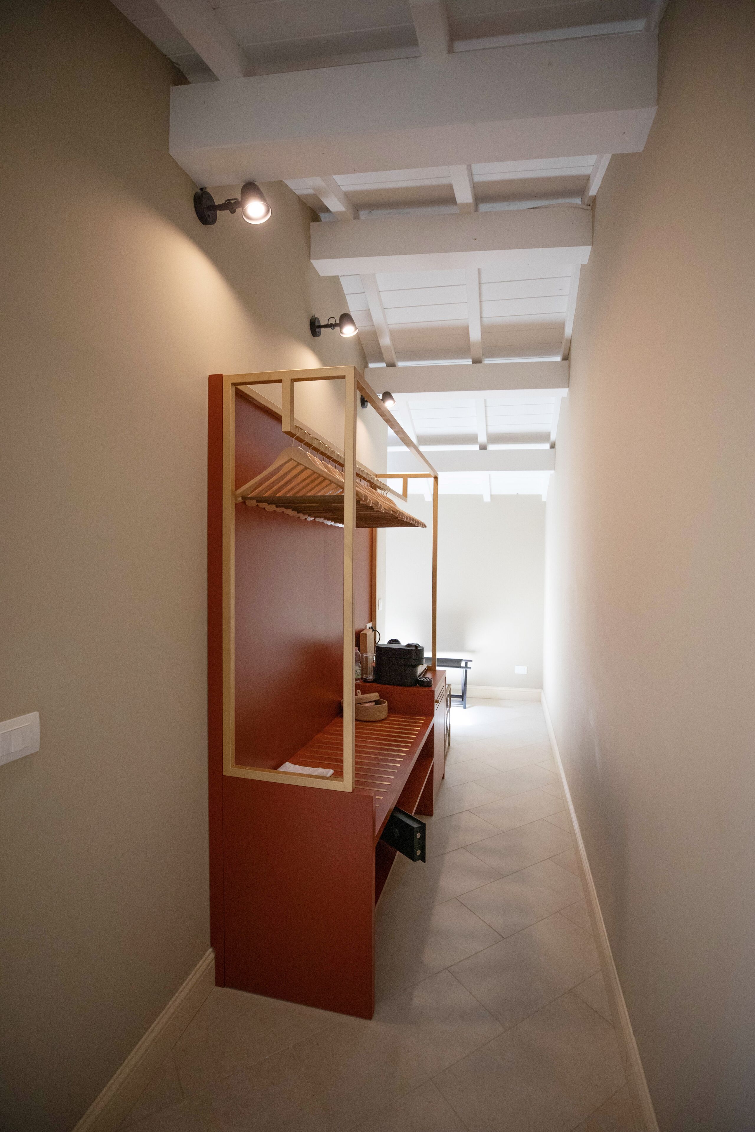 A narrow hallway with a wooden bench and a built-in bench with shelves.