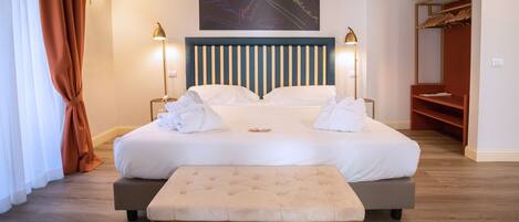 A neatly made bed with white linens, a tufted bench, and a headboard with vertical stripes.