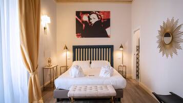 A hotel room with a large bed, two bedside tables, a bench, and a wall-mounted mirror.