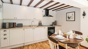 Une cuisine moderne avec des meubles blancs, un plafond en bois et un coin repas comprenant une table et des chaises en bois.