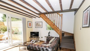 Un salon moderne avec un canapé en cuir, un plancher en bois, un téléviseur et un escalier.