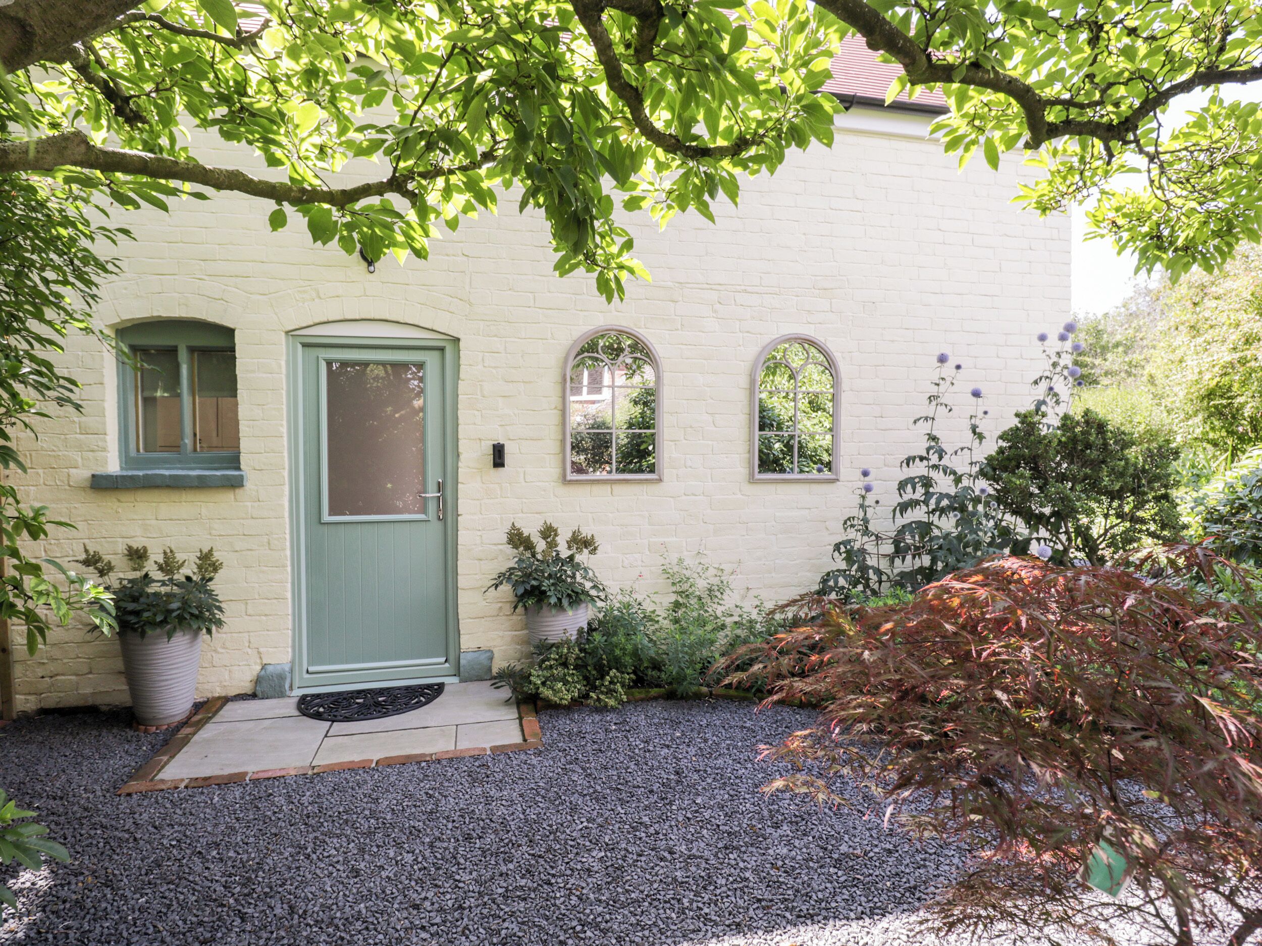 A house with a green door, two windows, and a gravel driveway.