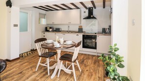 Une cuisine moderne avec des meubles blancs, une cuisinière noire et une table à manger en bois, accompagnée de chaises.