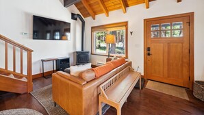Una sala de estar acogedora con un banco de madera, una chimenea, un televisor montado en la pared y una puerta de madera.