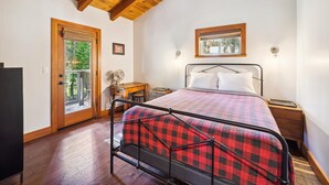 Un dormitorio con cama, mesitas de noche, una puerta de madera y una ventana.