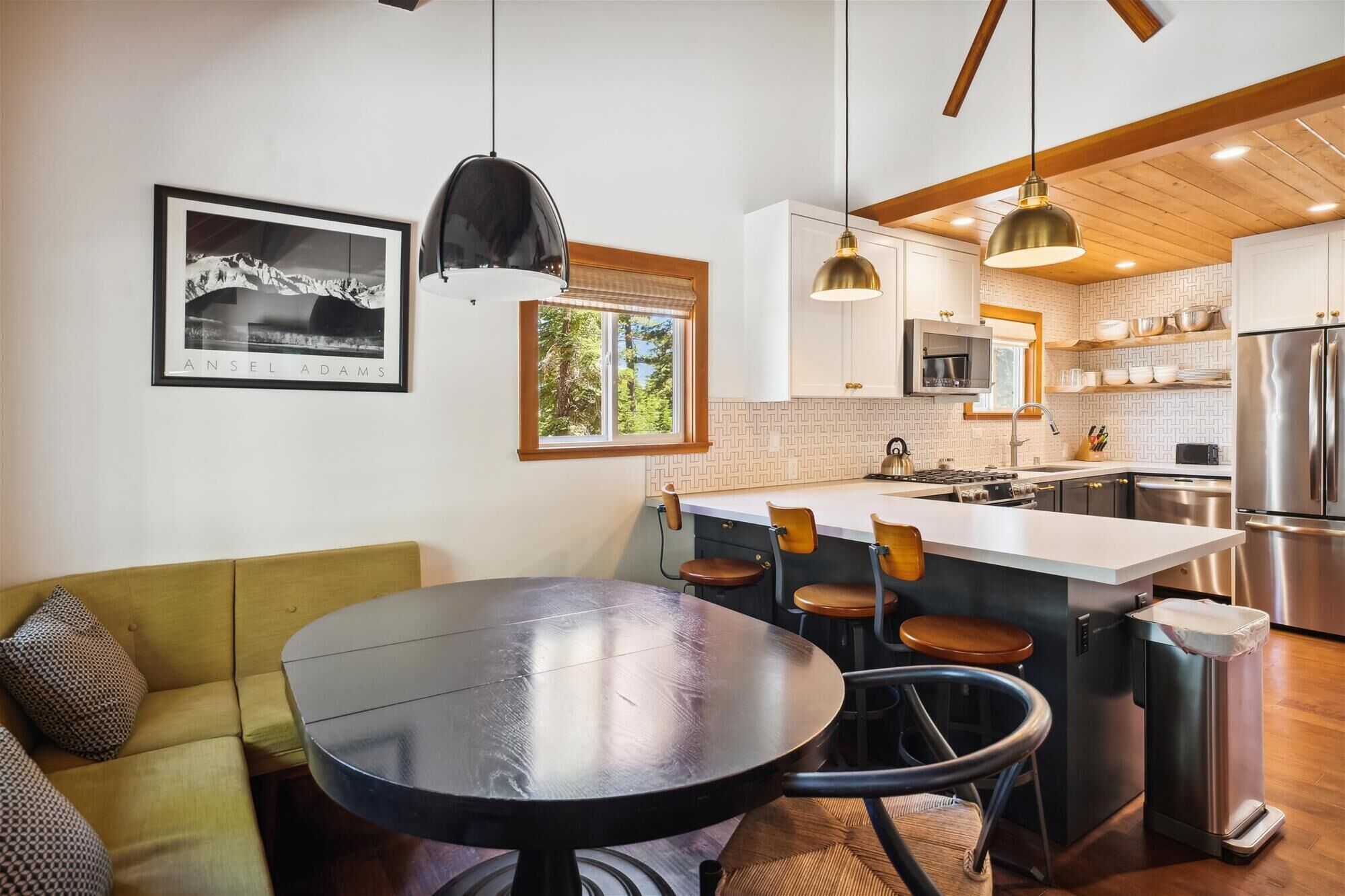 A modern kitchen with a central island, wooden ceiling beams, and pendant lighting.
