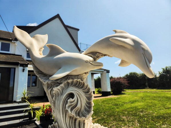 A sculpture of two dolphins on a decorative pillar. - Sea View - 1 Bed Suite - Port Eynon (Swansea)