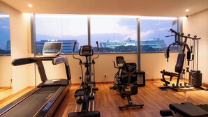 A gym with a treadmill, elliptical, and weight bench, large windows with a city view. - Golden Tulip Bhopal (Bhopal)