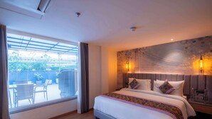A hotel room with a large bed, a view to the outside, a patterned wall, and a nightstand with a lamp. - Golden Tulip Bhopal (Bhopal)