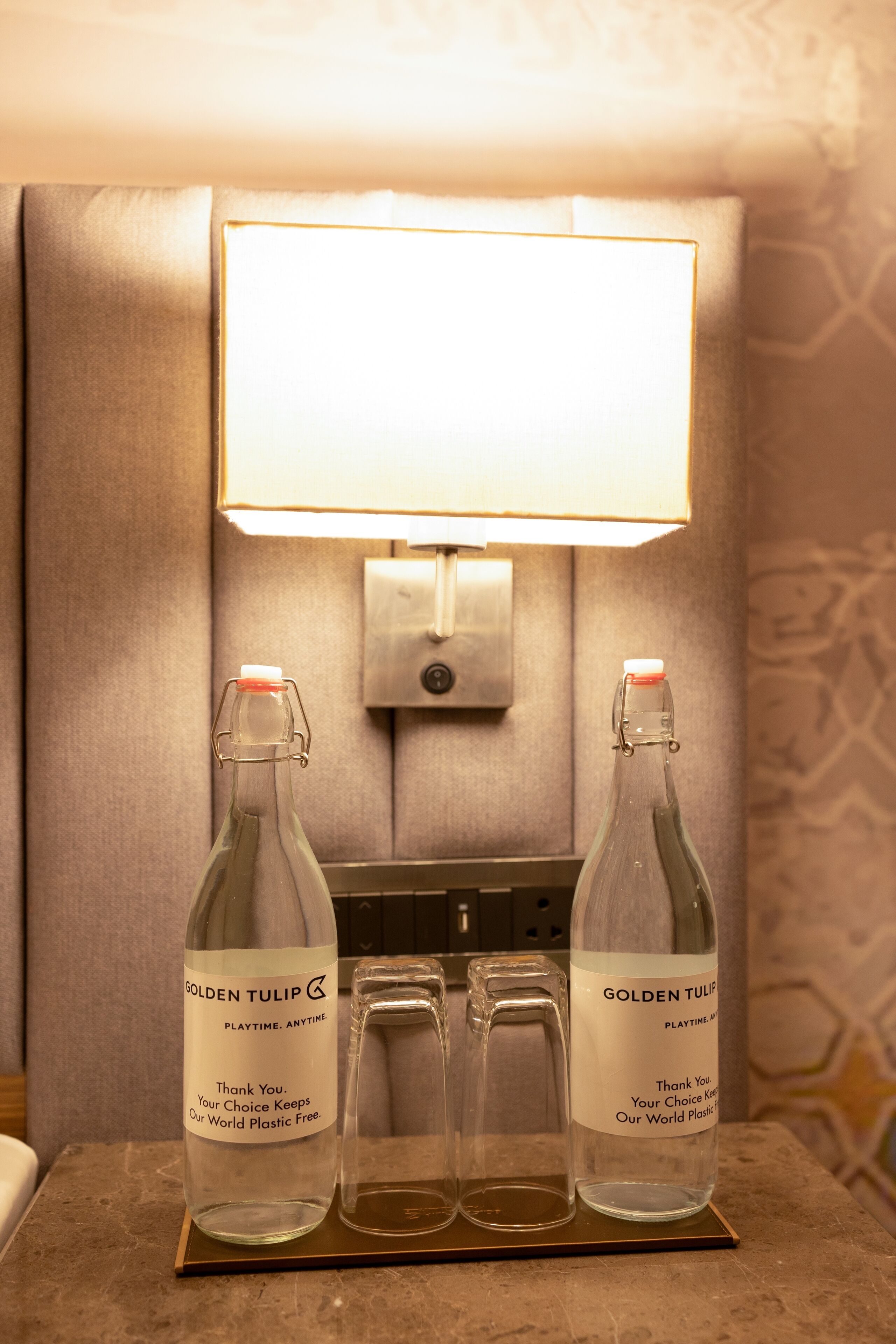 Two bottles of Golden Tulip Playtime, two glasses, and a wall-mounted light fixture.