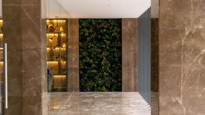 A corridor with marble flooring, a green wall with foliage, and a vertical light fixture. - Golden Tulip Bhopal (Bhopal)