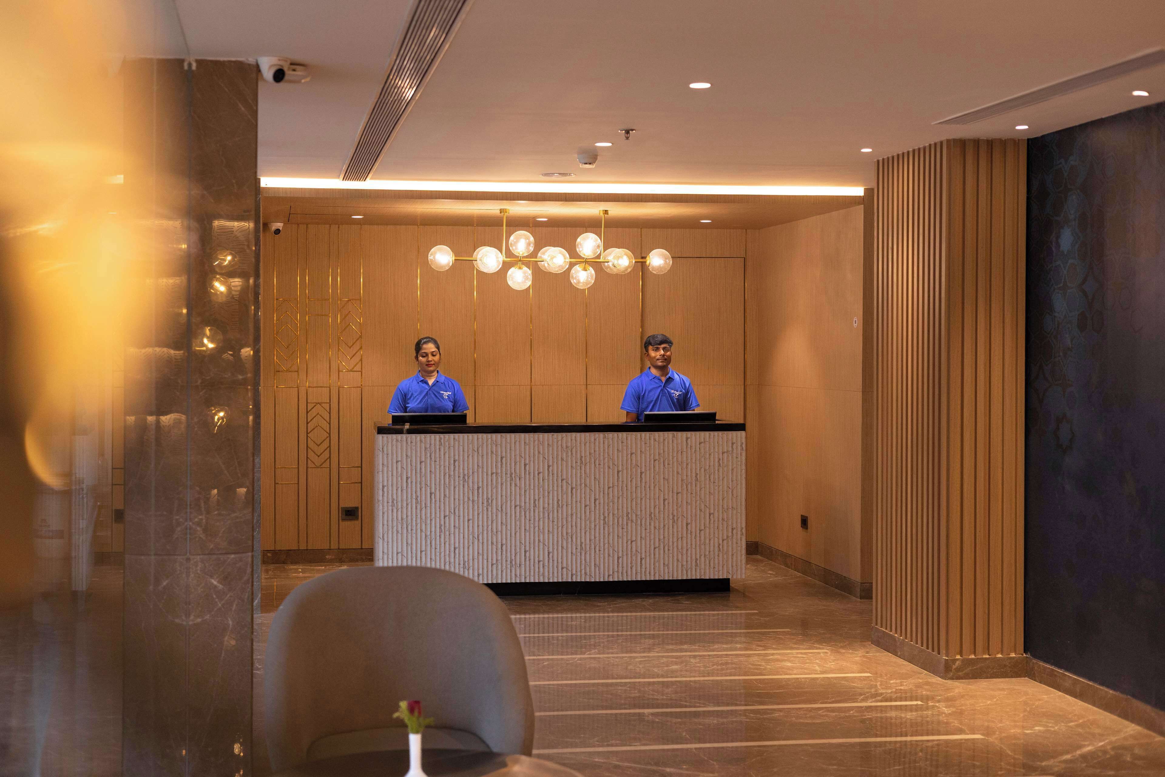 A reception area with two receptionists, a modern reception desk, and a marble floor.