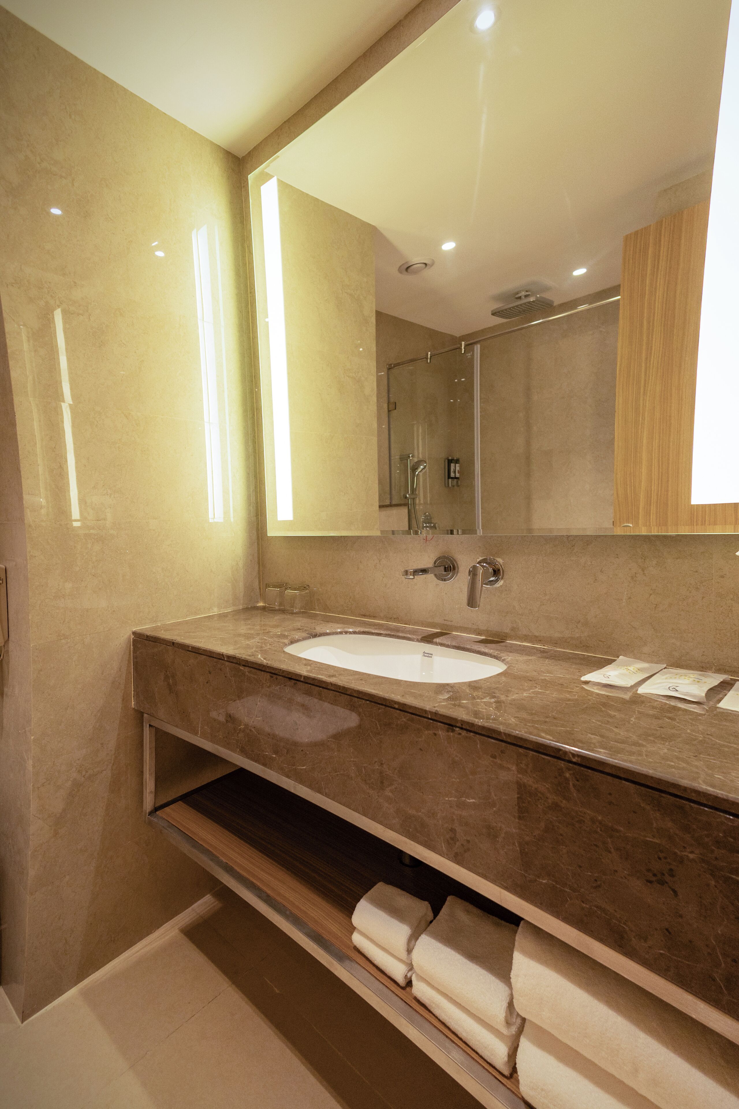 Un baño moderno con lavabo de mármol, un espejo grande y un perchero para toallas.