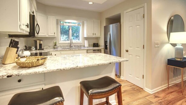 A modern kitchen with white cabinets, a large island, stainless steel appliances, and a window providing natural light. - Chetola Resort, Pine #3, in Blowing Rock (Blowing Rock)