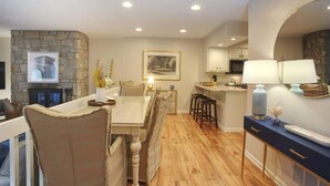 A modern kitchen with a stone accent wall, wooden flooring, and a dining area with a table and chairs. - Chetola Resort, Pine #3, in Blowing Rock (Blowing Rock)