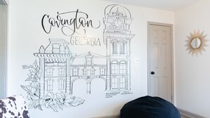 A wall with a line drawing of a building and the text "Cavinton Georgia" along with a floral design. - Blue Bungalow w/ Free Golf Cart (Covington)