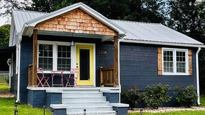 A two-story house with a front porch, a yellow door, and a mailbox. - Blue Bungalow w/ Free Golf Cart (Covington)