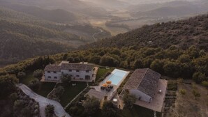 Una villa con piscina, rodeada de exuberante vegetación y colinas.