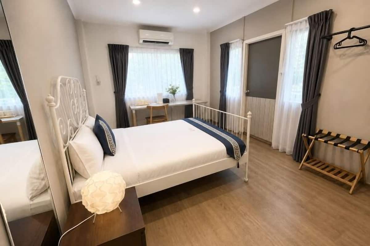 A bedroom with a bed, bedside table, lamp, and a window with curtains.