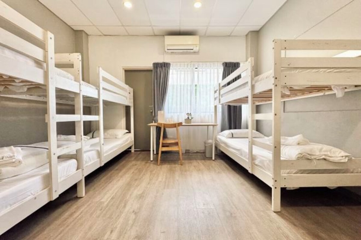 Una habitació de dormitori amb lliteres, escriptori i finestra amb cortines.