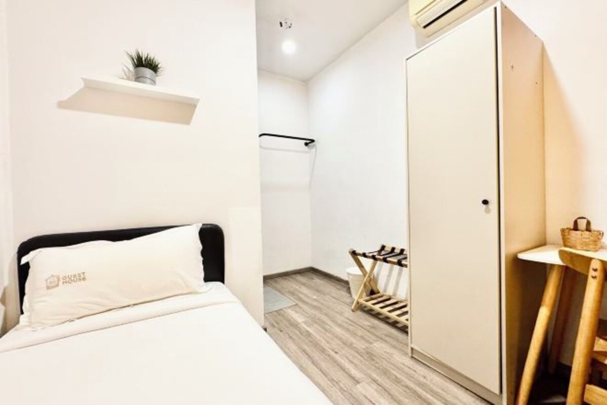 Habitació d'hotel moderna amb un llit, un armari, una taula petita i una banca.
