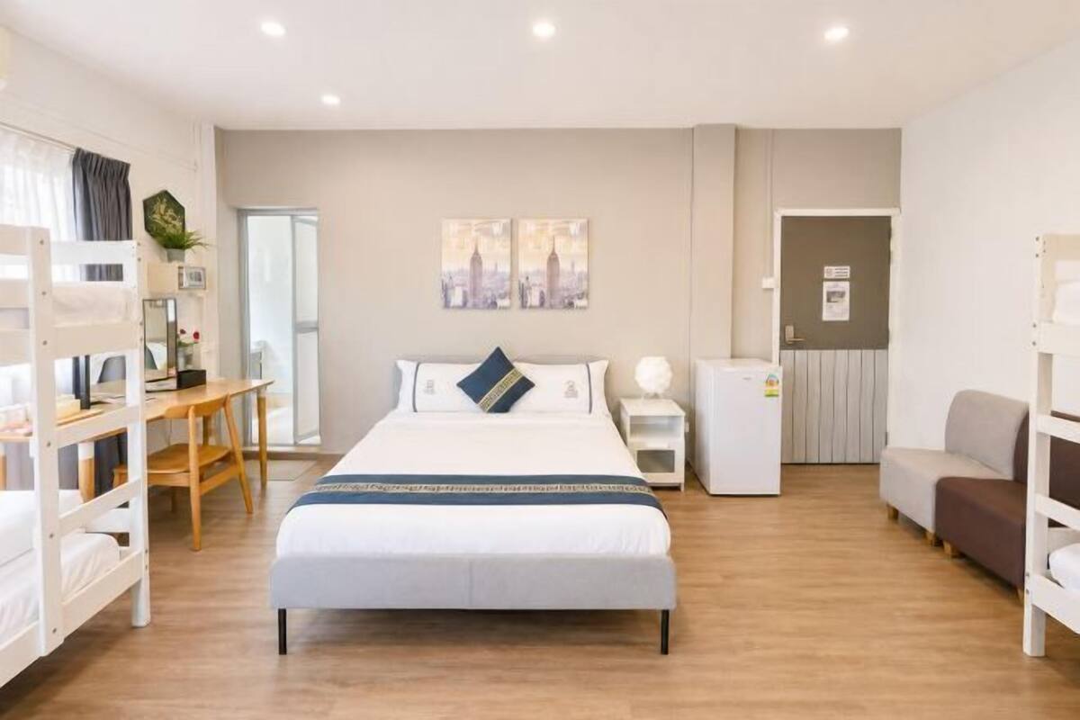 A modern hotel room with a bed, desk, chair, and a small table.
