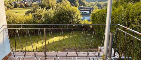 Ein Balkon mit Blick auf eine grüne Landschaft und ein Haus in der Ferne.