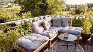 A wooden deck with a cushioned seating area, a small round table, and a patterned rug.