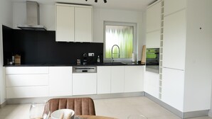 A modern kitchen with white cabinets, a black countertop, and a dining area with a table set for two.