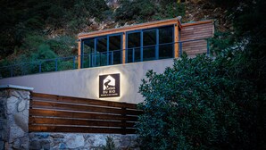 Un bâtiment moderne avec une base en pierre, des lambris en bois et une enseigne indiquant « CASAS DU RIO NATURE & ECO HOUSES ».