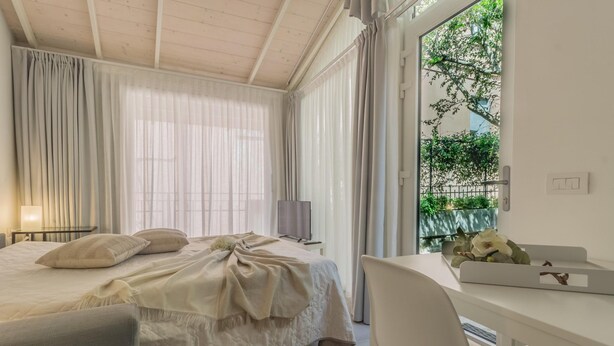 Ein Schlafzimmer mit einem Bett, einem Schreibtisch und einem Fenster mit Vorhängen.
