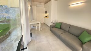 Ein modernes Wohnzimmer mit grauem Sofa, einem Esstisch und einer Küchenzeile.