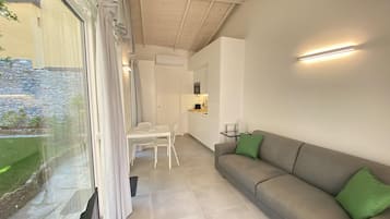 Un salon moderne avec un canapé gris, une table à manger et un coin cuisine.