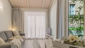Ein modernes Wohnzimmer mit einer Couch, einem Esstisch und einem Fernseher auf einem Schrank.