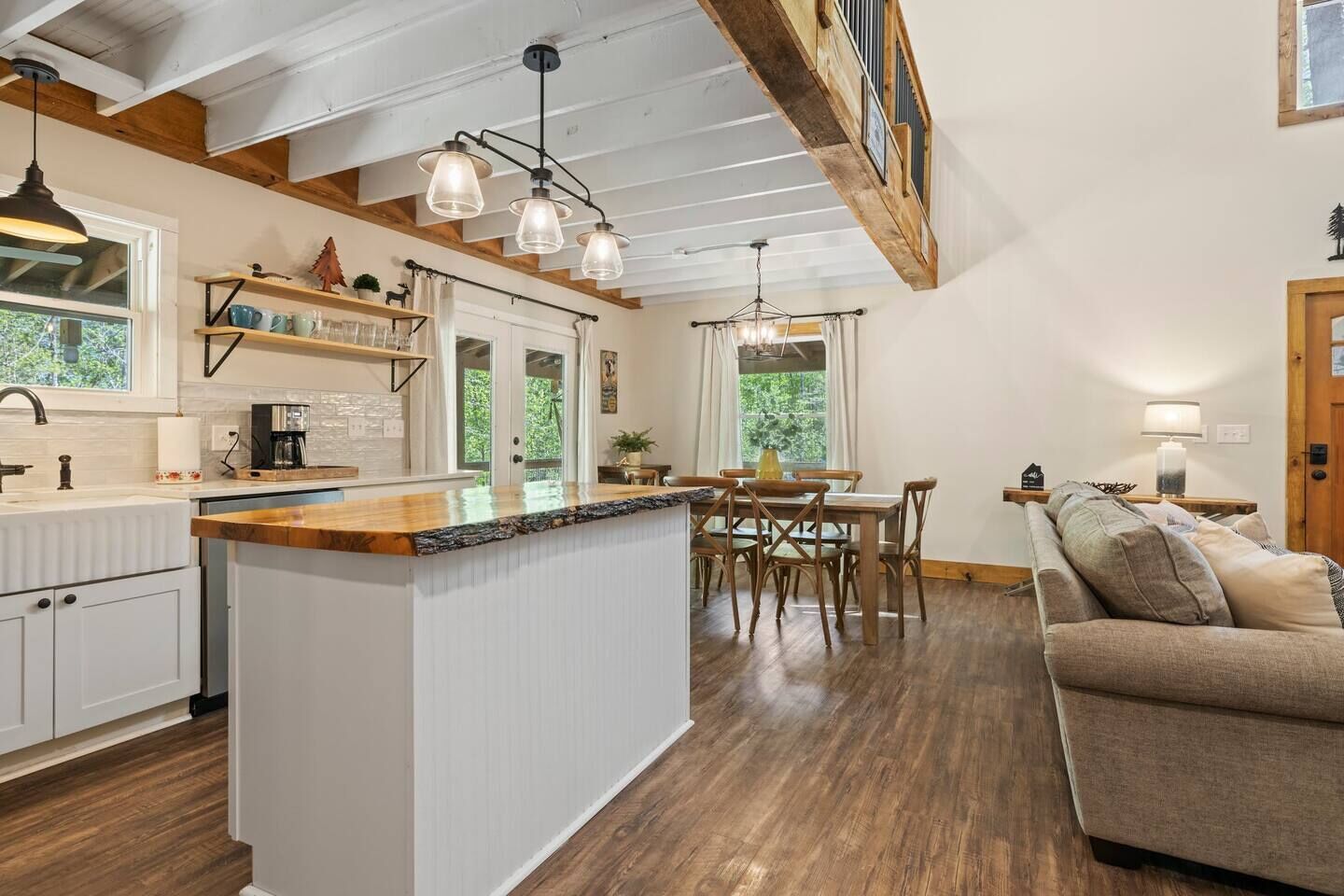 A modern kitchen with a central island, wooden beams, and pendant lighting.