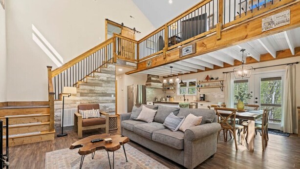 Ein geräumiger Wohnbereich mit einer Holztreppe, einem grauen Sofa und einem Esstisch.