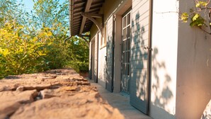 A stone pathway leading to a building with a wooden roof and a garage door. - La Villa des Gones (Dommartin)