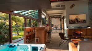 A modern kitchen with a large island, bar area, and a hot tub. - La Villa des Gones (Dommartin)
