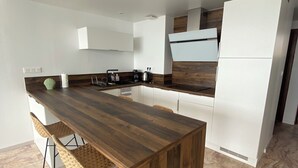 A modern kitchen with a wooden island, white cabinets, and a built-in oven.