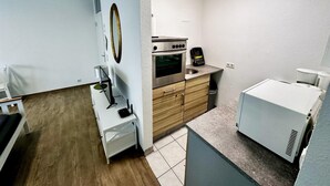 Una cucina compatta con frigorifero, microonde, forno e lavello.