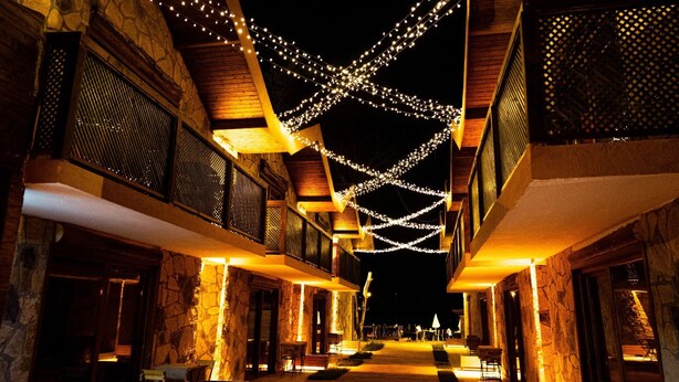 A hotel corridor with stone walls, wooden balconies, and string lights. - Taş Mahall Luxury Hotel (Sile)