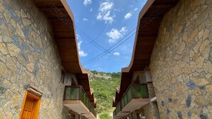 A pathway leading to a building with stone walls and wooden beams, benches, and a view of the sky. - Taş Mahall Luxury Hotel (Sile)