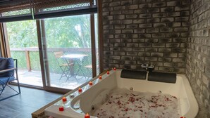 A spa area with a large bathtub, candles, and a view of the outdoors. - Taş Mahall Luxury Hotel (Sile)