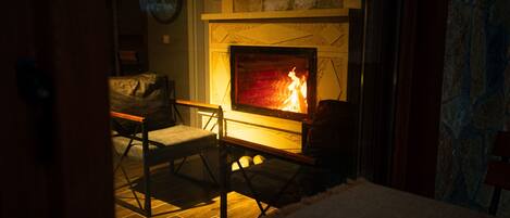 A cozy room with a fireplace, two chairs, and a sofa.